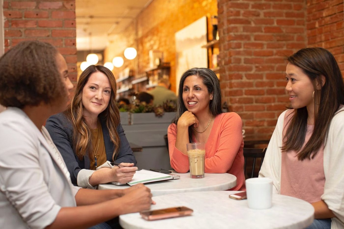 Quatro mulheres à volta de uma mesa, em conversa